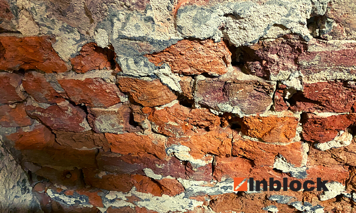 Uszkodzenia muru ściany fundamentowej z czerwonej cegły